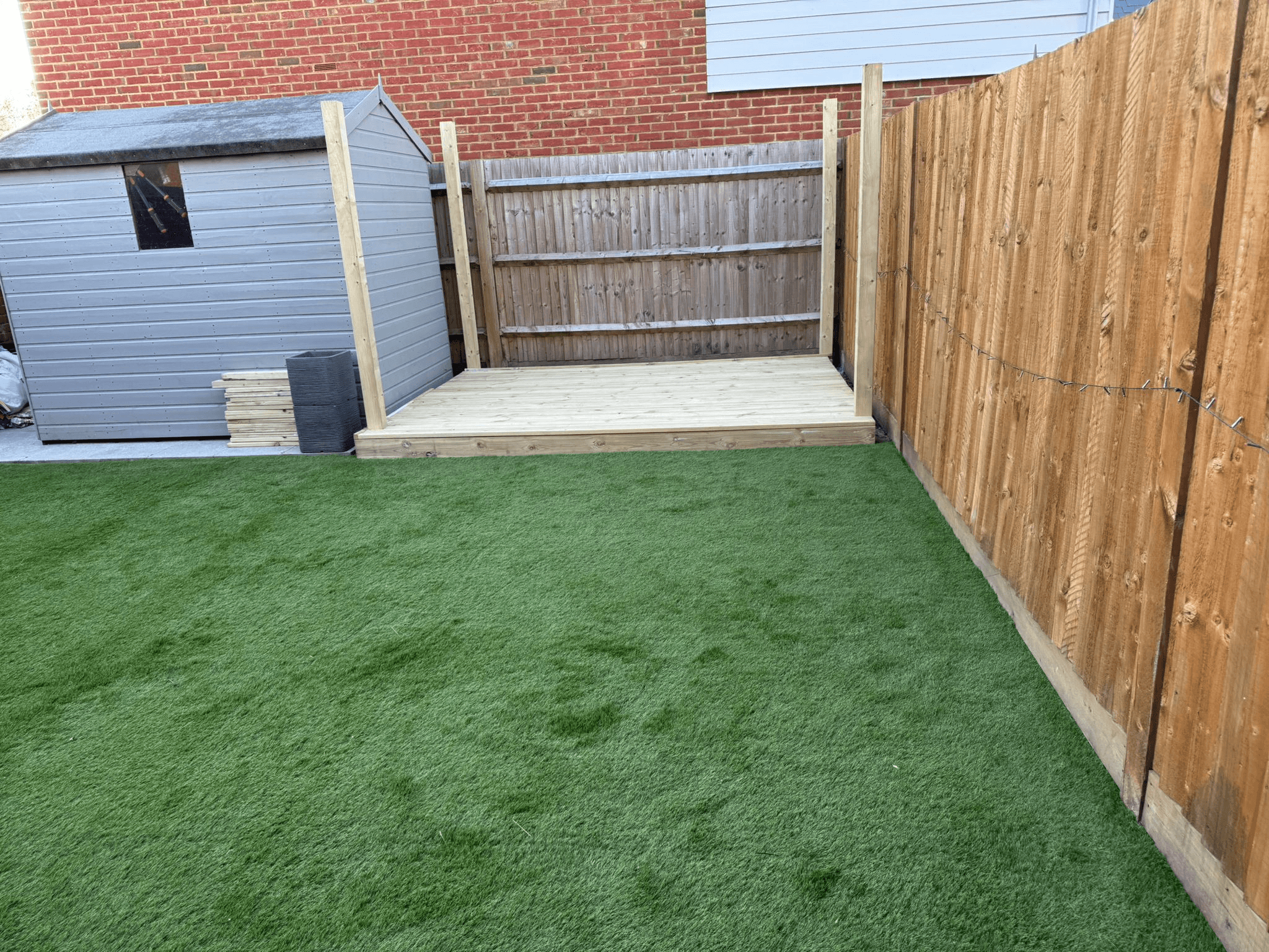 Garden with artificial grass, decking platform and shed